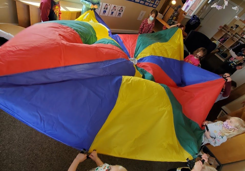 Children waving a colorful parachute.